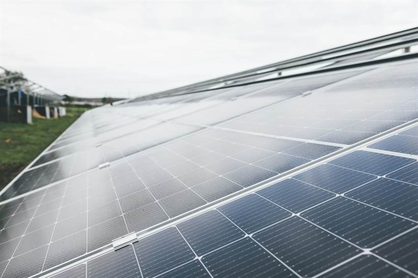Casa com módulos fotovoltaicos instalados no telhado, cercada por árvores